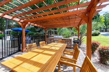 Picnic area under a wooden pergola with a grill at Laurel Springs in Raleigh, NC.